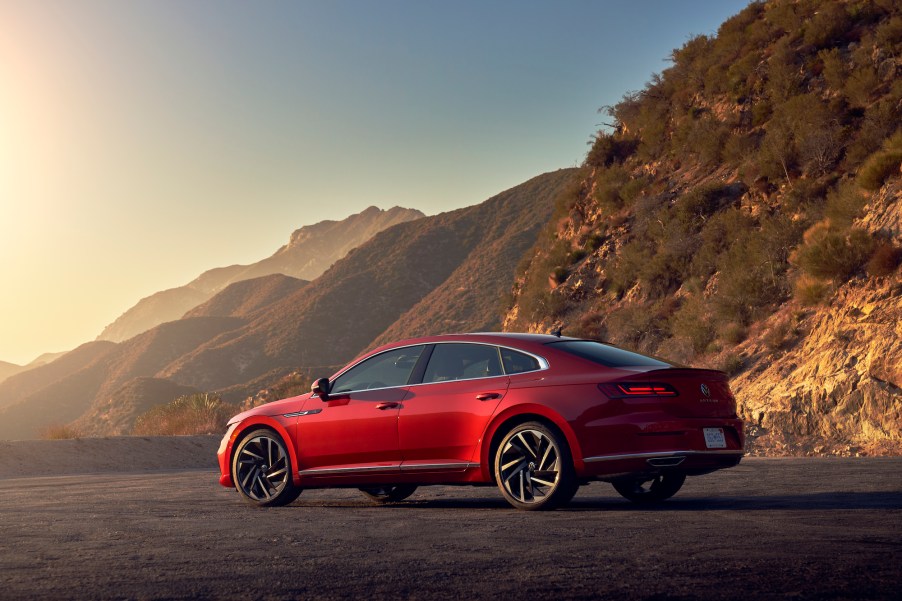 A red 2021 Volkswagen Arteon sedan parked in front of mountains on a sunny day