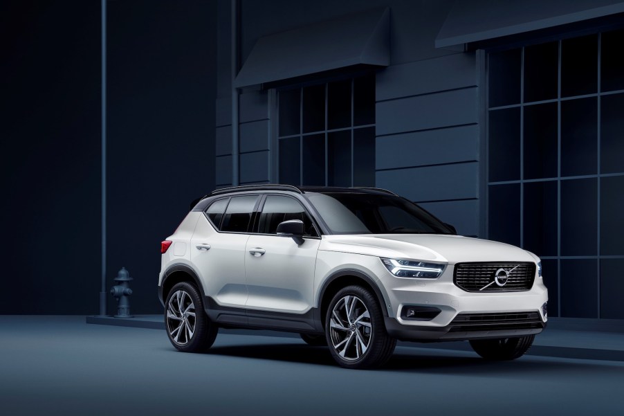 A 2021 Volvo XC40 R-Design in Crystal White Pearl parked on a curb next to a building and fire hydrant