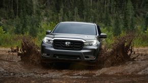 a 2021 honda ridgeline splashing through a muddy trailway in the forest