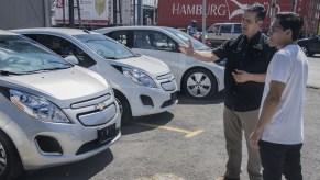 A salesman talking to a customer about new cars and used cars while next to Chevrolet models