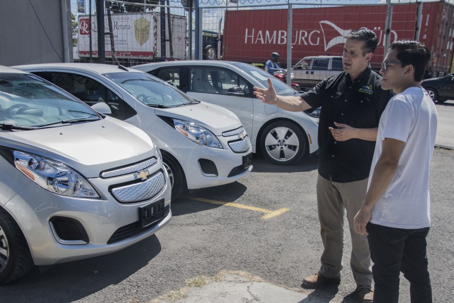 A salesman talking to a customer about new cars and used cars while next to Chevrolet models