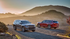 A gray-brown 2021 Jeep Grand Cherokee L Summit Reserve and a red Overland on a foggy hill