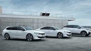 Three white Peugeot plug-in hybrid models are parked next to each other.