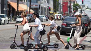 Women ride electric scooters in Santa Monica, California.