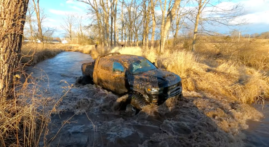 An image of a broken 2021 Ram 1500 TRX on enormous tires off-road.