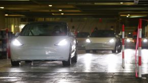 Staff members drive Tesla Model 3 vehicles out of a vessel at Zeebrugge port, Belgium