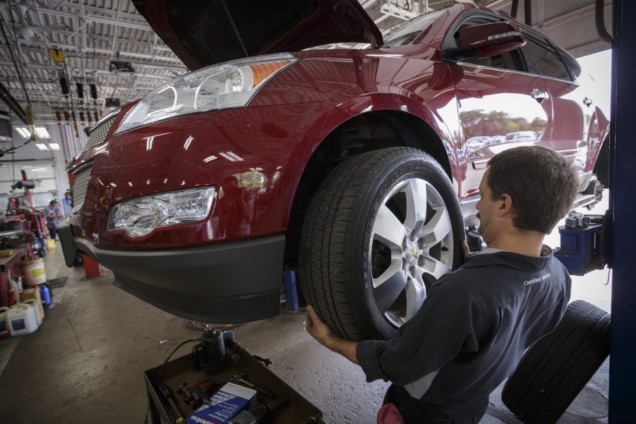 Technician Dave Serdar rotates the tires on a Chevy Traverse