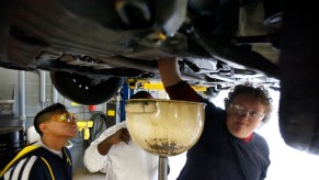 Two high school students change a car's engine oil