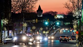 Various cars with their headlights on driving down a city road at dusk