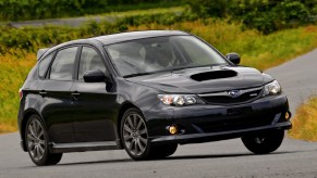 A black 2009 Subaru Impreza WRX hatch on a backcountry road