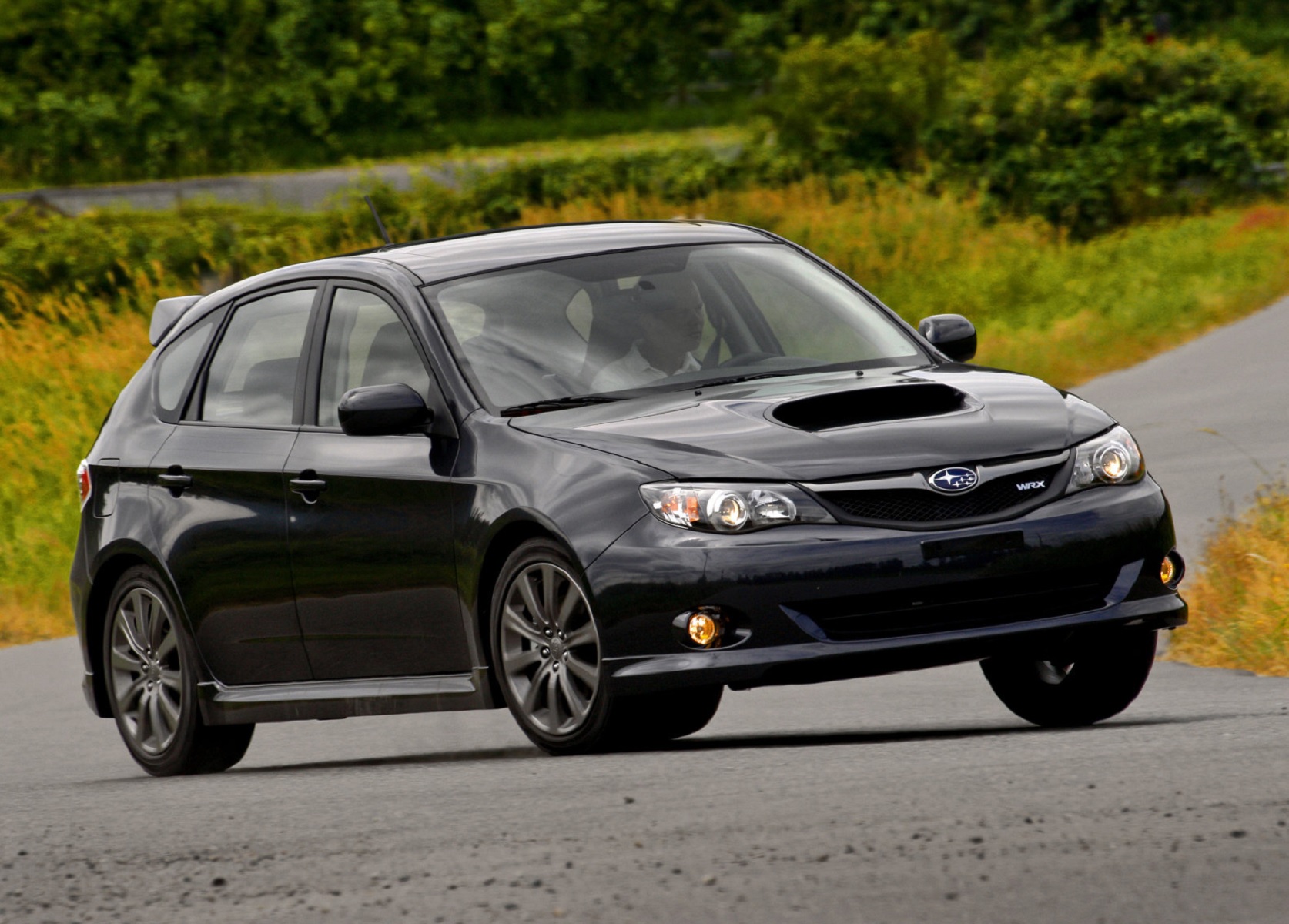 A black 2009 Subaru Impreza WRX hatch on a country road