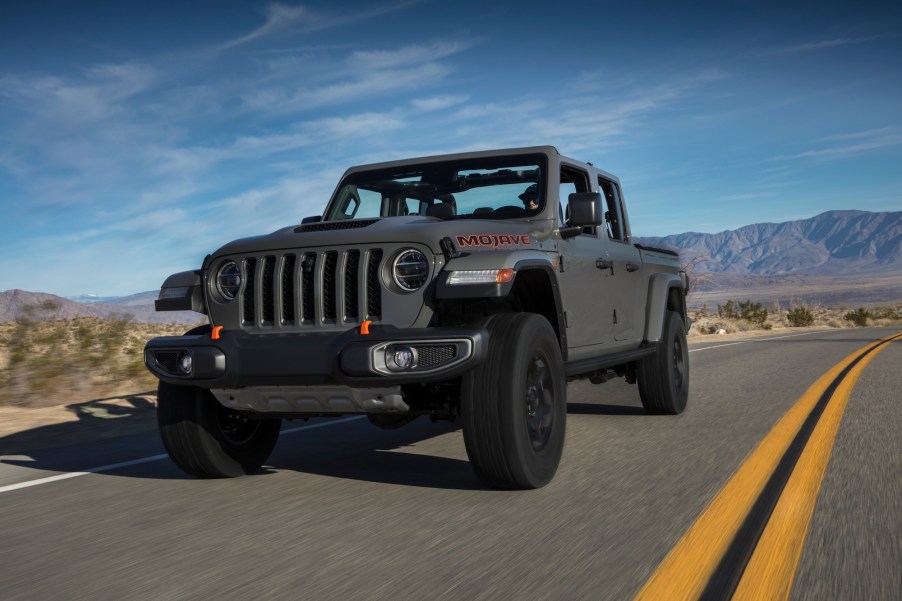 A gray 2020 Jeep Gladiator Mojave traveling on a two-lane highway in a mountainous desert