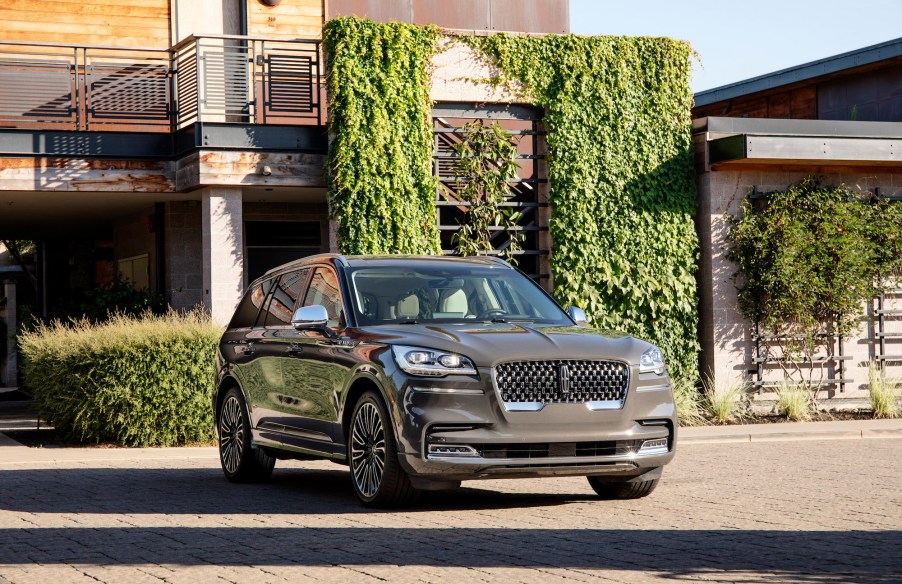 A gray 2020 Lincoln Aviator midsize crossover SUV parked outside a modern ivy-covered home