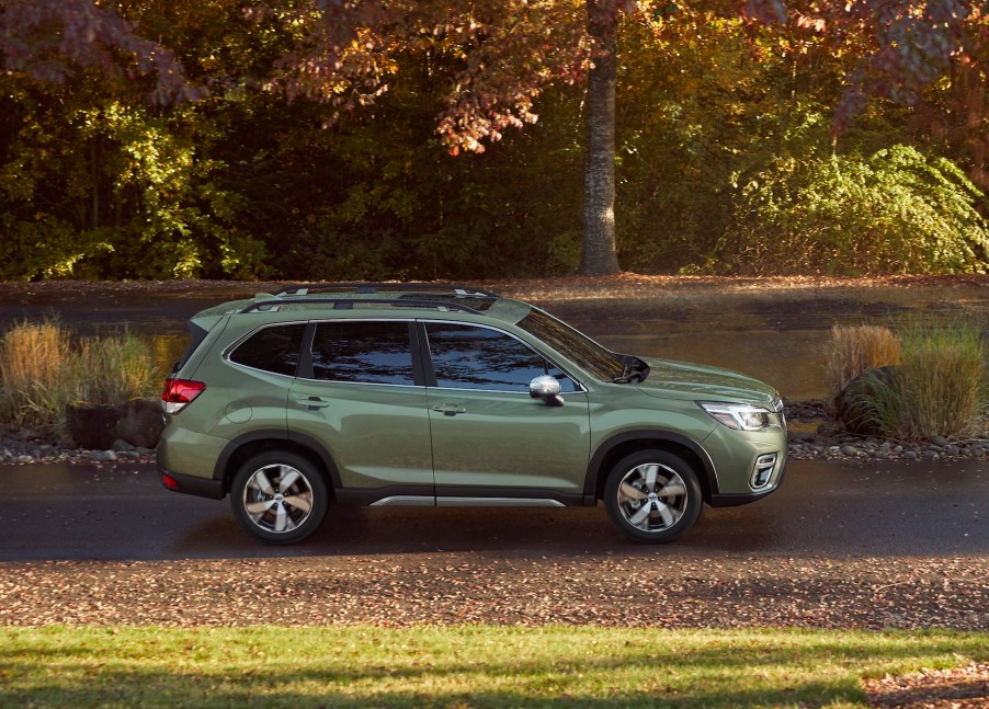 A green 2020 Subaru Forester compact crossover SUV parked on a sunny, tree-lined road