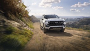 A front-facing look at a white 2021 Chevy Tahoe Z71 driving down a dirt road