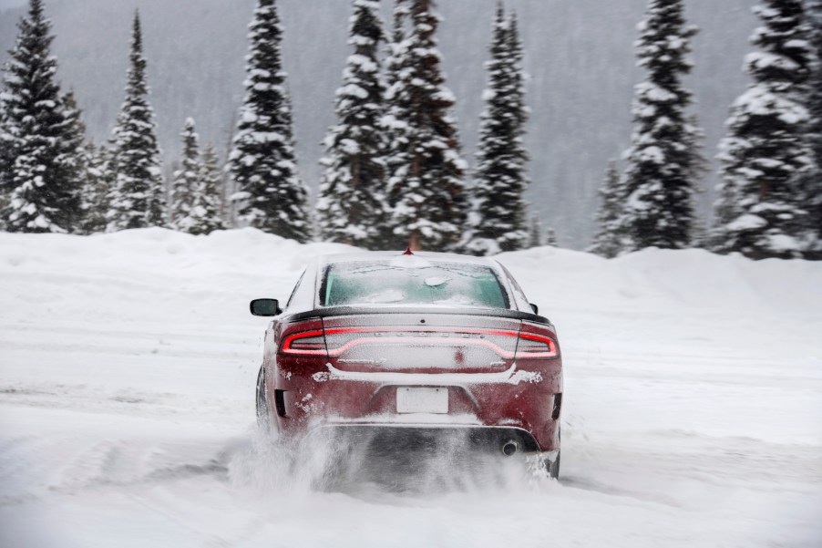 A rear view of a red 2021 Dodge Charger GT all-wheel drive driving in the snow