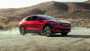 A red 2021 Ford Mustang Mach-E kicks up dust in a desert