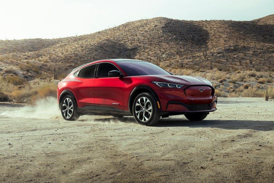 A red 2021 Ford Mustang Mach-E kicks up dust in a desert