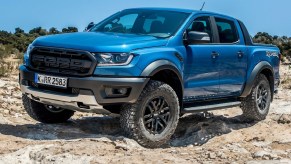 A blue 2021 Ford Ranger Raptor crawls over some desert rocks