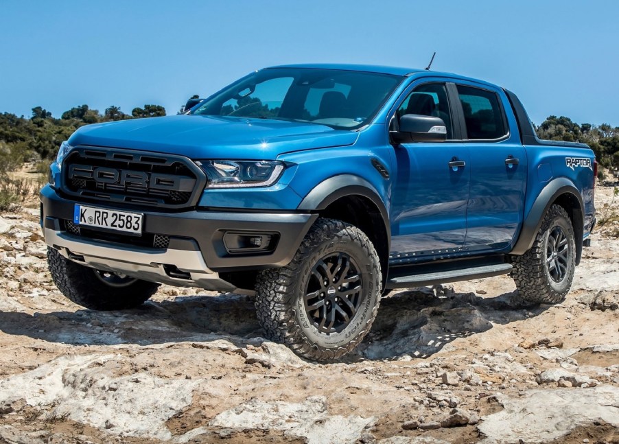 A blue 2021 Ford Ranger Raptor crawls over some desert rocks