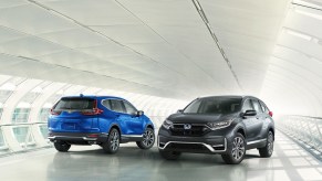 A blue 2021 Honda CR-V parked next to a CR-V Hybrid on a white covered bridge