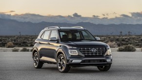 A black 2021 Hyundai Venue subcompact SUV parked on a road in a desert with mountains in the background