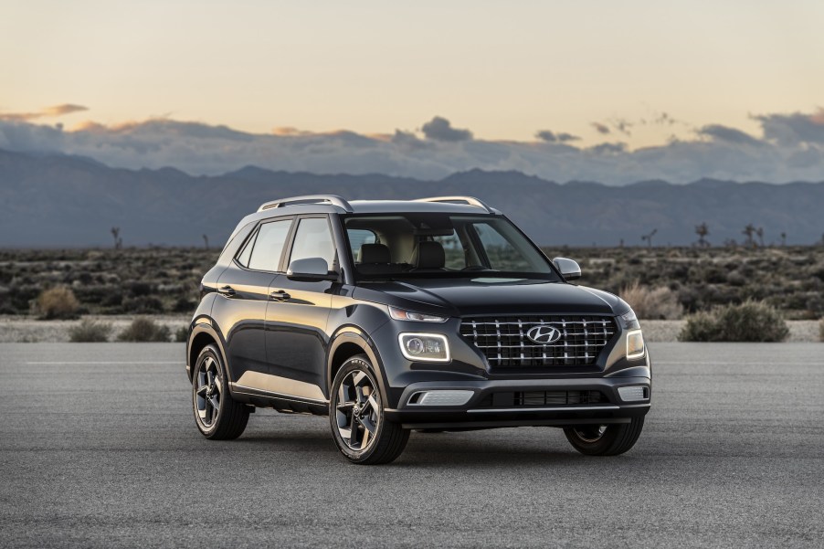 A black 2021 Hyundai Venue subcompact SUV parked on a road in a desert with mountains in the background