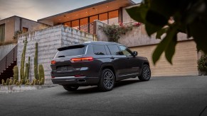 A dark-gray 2021 Jeep Grand Cherokee L Summit Reserve parked in a modern desert home's driveway