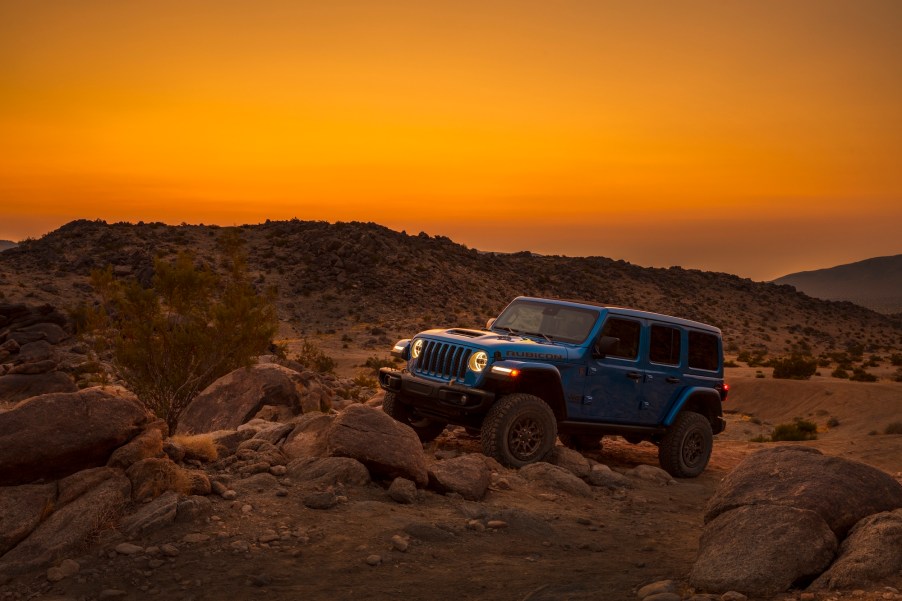 A blue 2021 Jeep Wrangler Rubicon 392 SUV parked on rocks at sunset in mountainous terrain