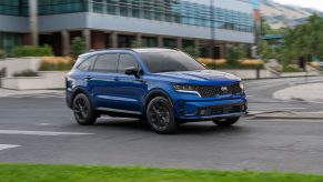 A blue 2021 Kia Sorento SX on display in a parking lot with a building in the background