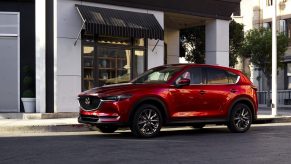 A luxurious red 2021 Mazda CX-5 parked in front of a building