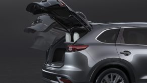 An action shot of a silver 2021 Mazda CX-9's liftgate opening, revealing its small cargo area.