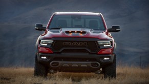 A red 2021 Ram 1500 TRX parked in a field of dry weeds in front of mountains at dusk