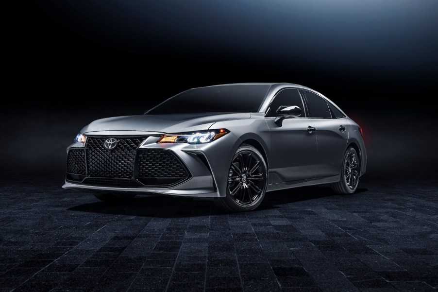 A silver 2021 Toyota Avalon XSE Nightshade full-size sedan parked on a black carpet in a dimly lit room