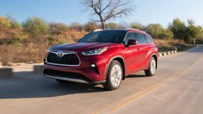 A red 2021 Toyota Highlander Hybrid driving down a road