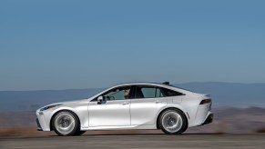 A 2021 Toyota Mirai Limited in Oxygen White traveling on asphalt with a mountain backdrop