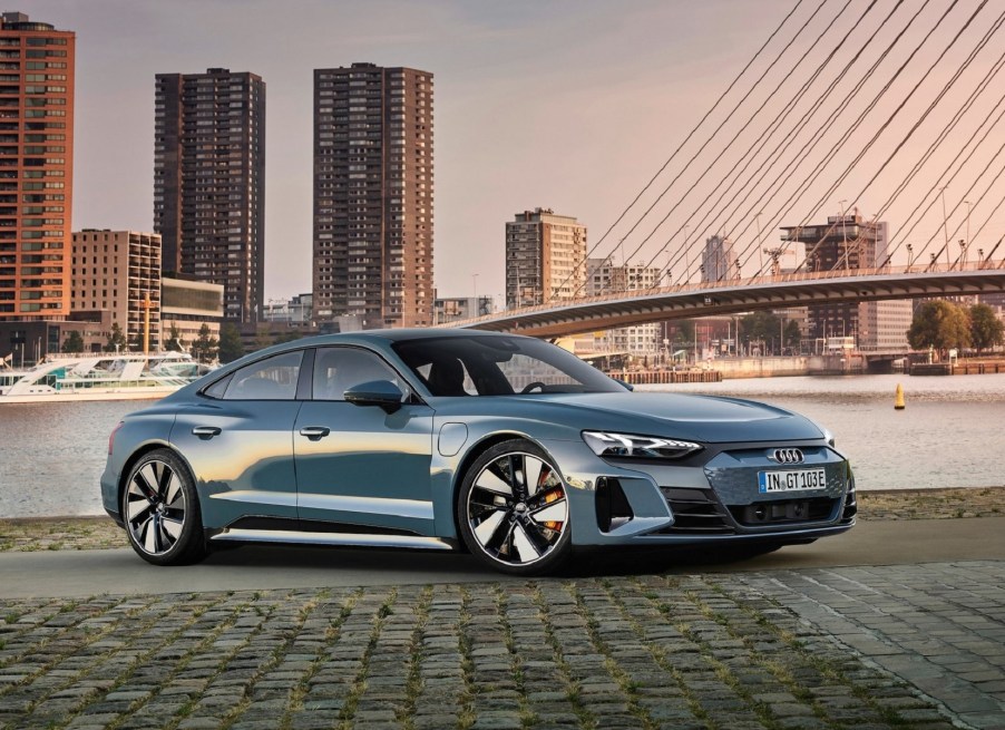 A blue-gray 2022 Audi E-Tron GT Quattro by a bayside city at sunset