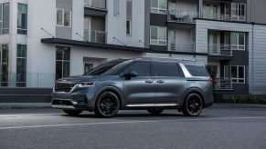 A turquoise 2022 Kia Carnival driving down a city road