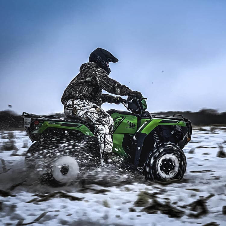 a bright green honda fourtrax foreman rubicon in the snow