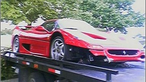 An image of a crashed Ferrari F50 on the back of a flatbed tow truck.