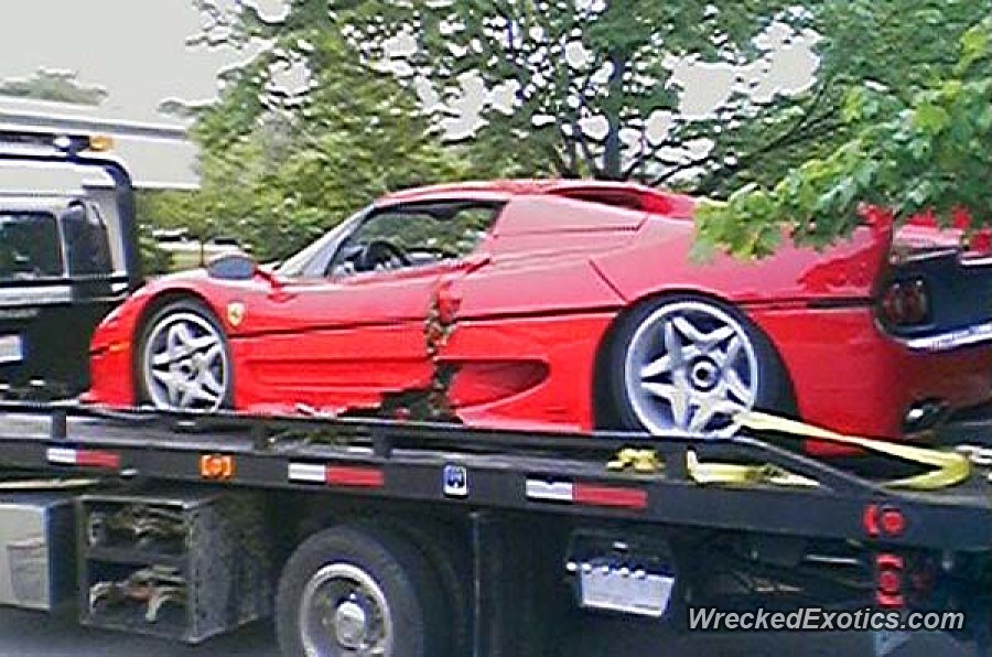 An image of a crashed Ferrari F50 on the back of a flatbed tow truck.