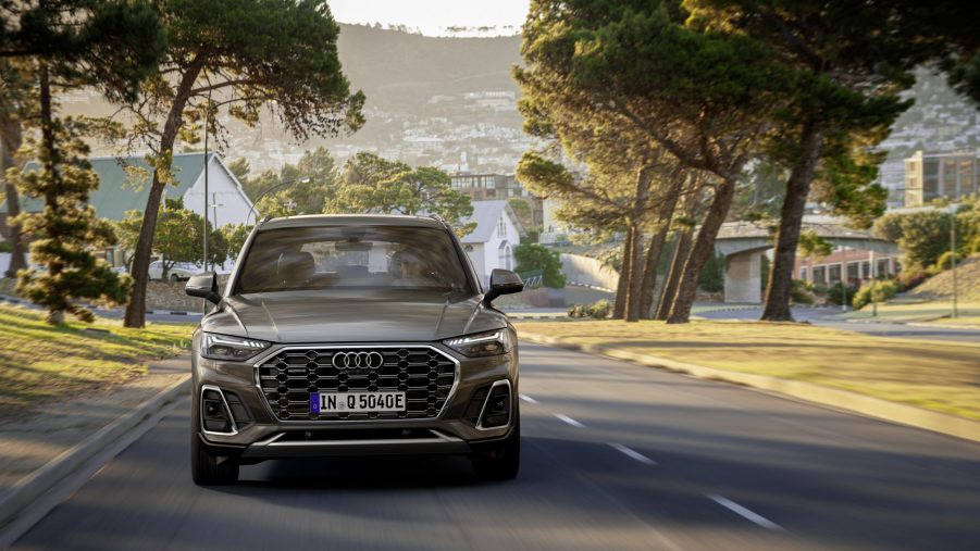 A Audi Q5 55 TFSI e quattro in Daytona grey driving through a shaded roadway