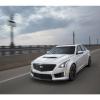 a white 2019 cadillac CTS at speed on an urban bridge