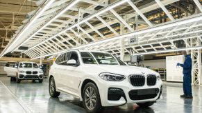 A worker wearing a protective face mask checks the bodywork of an BMW X3 sport utility vehicle (SUV) in a light tunnel at the BMW South Africa Pty Ltd. Rosslyn plant