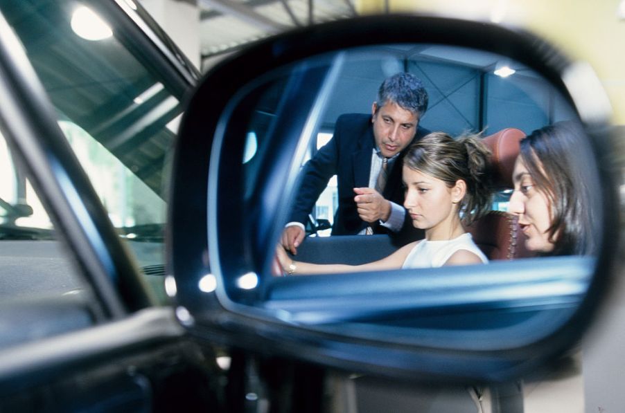 mirror reflection of woman being sold car by salesman