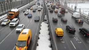 Cars and other vehicles drive on a snowy divided highway