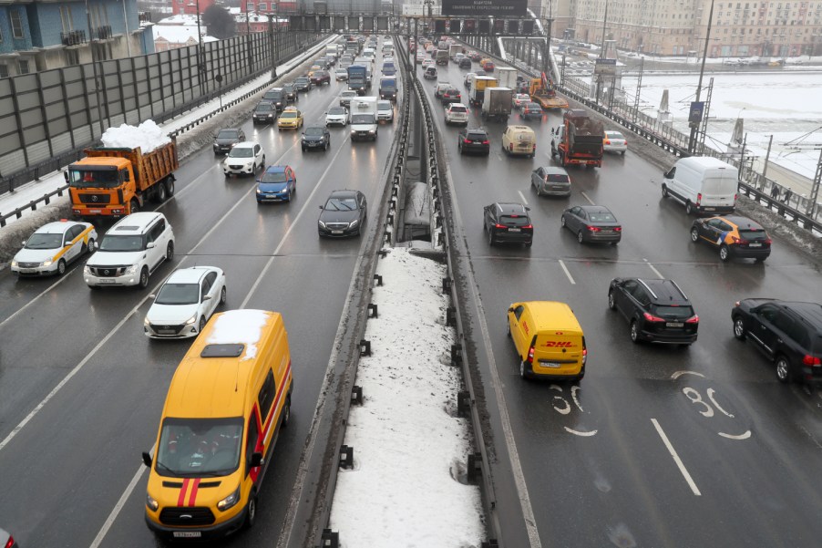 Cars and other vehicles drive on a snowy divided highway