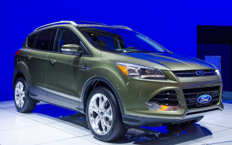 A green 2013 Ford Escape on display in front of a blue wall