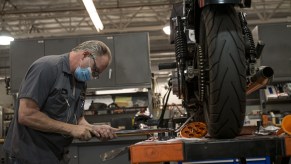 A person adjusting a Harley-Davidson motorcycle with a wrench