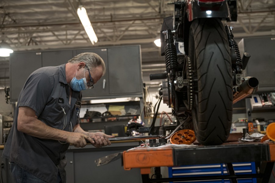 A person adjusting a Harley-Davidson motorcycle with a wrench